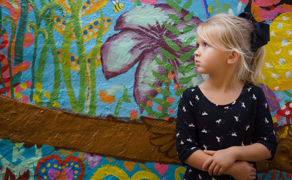 Child standing in front of a wall mural